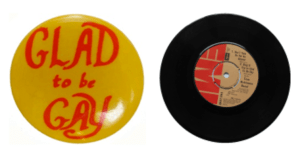 Photograph of Glad to be Gay badge next to Tom Robinson Glad to be Gay single.